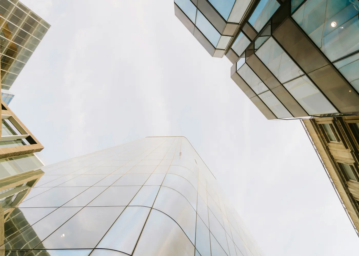 Glass office towers seen from below against a pale sky